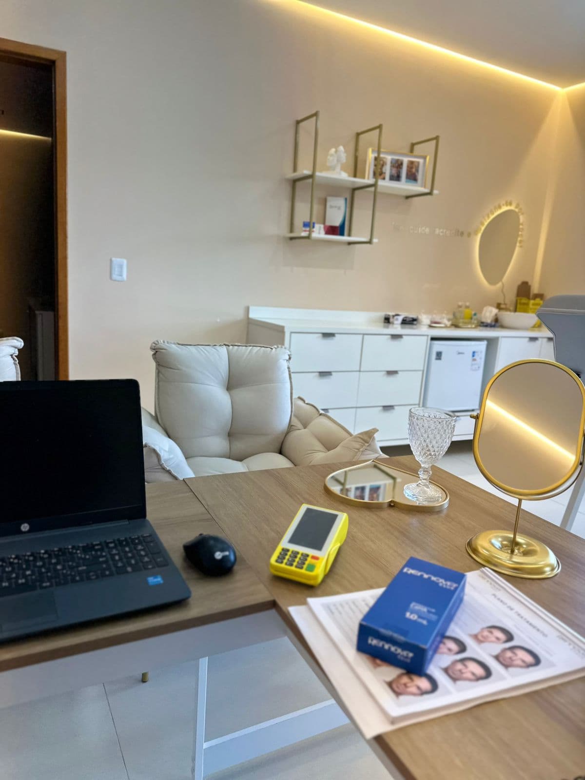 Interior da clínica: poltrona de atendimento, bancada branca e espelho dourado